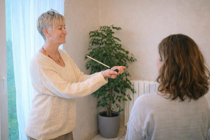 Photo de Carole Blériot en séance de centrage énergétique dans un environnement calme et naturel, utilisant l’antenne de Lecher face à une personne. Cette image illustre un recentrage manuel visant à rétablir l’équilibre et la circulation des énergies.